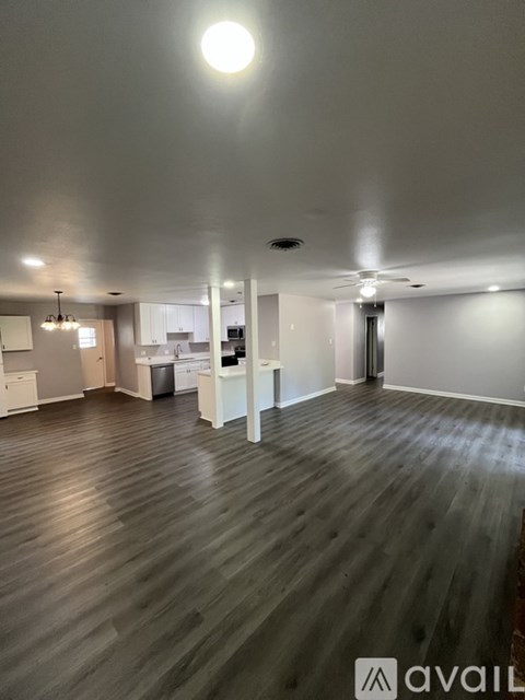 A spacious room with wooden flooring and a ceiling fan.