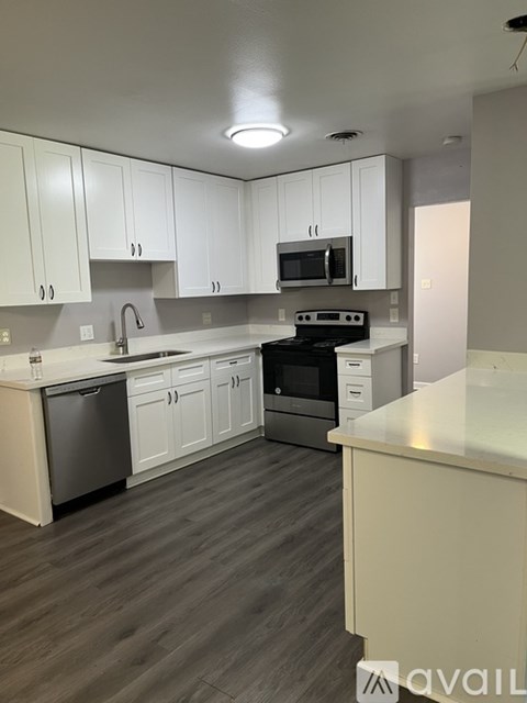 A kitchen with white cabinets and a wooden floor.