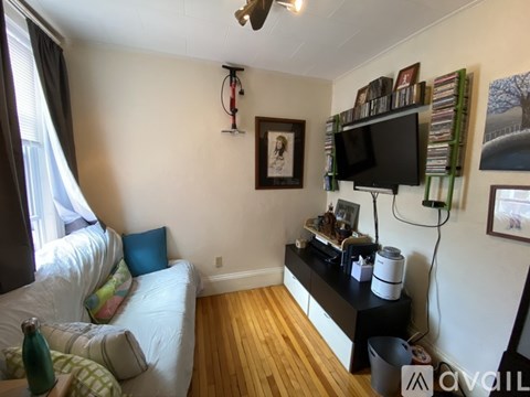 A living room with a white couch and a television on a stand.