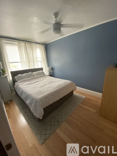 A bedroom with a bed, a ceiling fan, and a window with curtains.