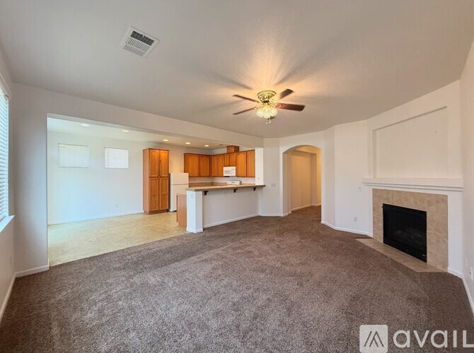 A spacious living room with a fireplace and a ceiling fan.