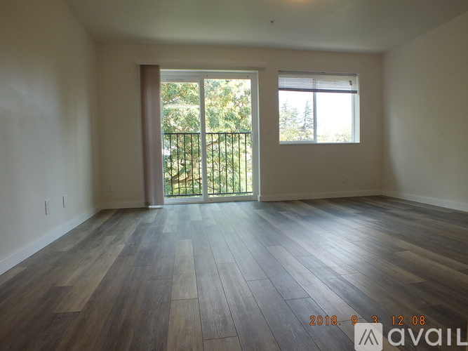 A room with wooden floors and a sliding glass door leading to a balcony.