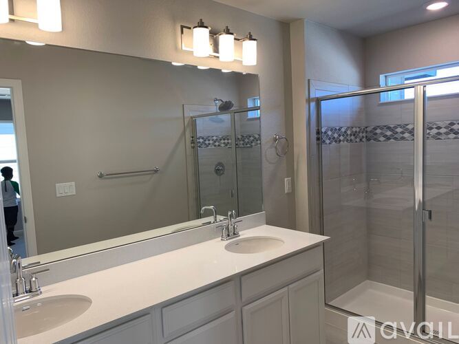 A bathroom with a sink, mirror, and shower.