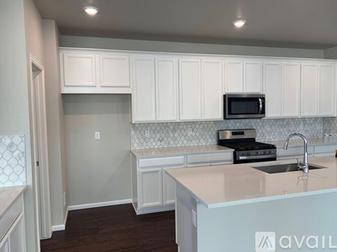 A kitchen with white cabinets and a countertop with a sink and stove.