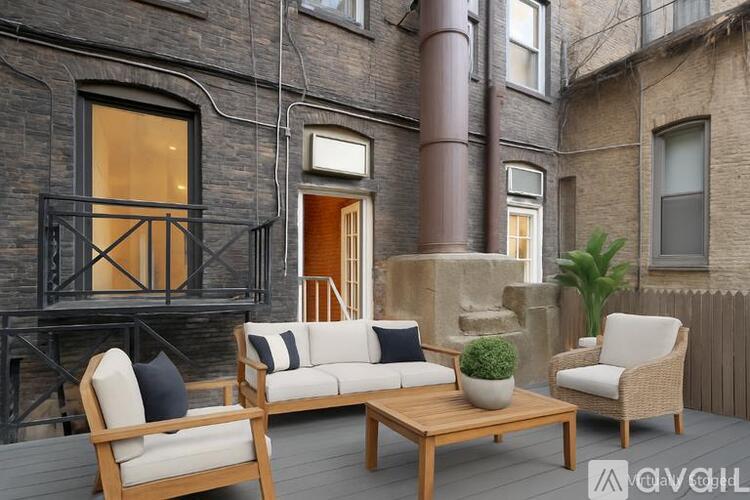 A patio with a white couch, two chairs, and a table with a plant on it.