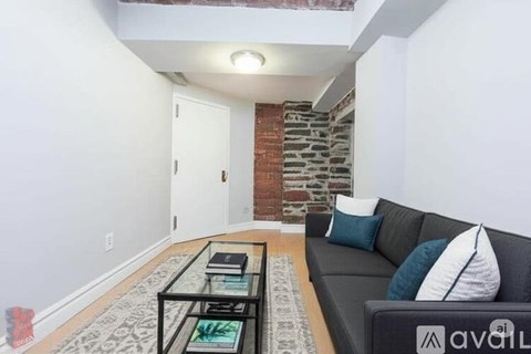 A living room with a black couch and a glass coffee table.