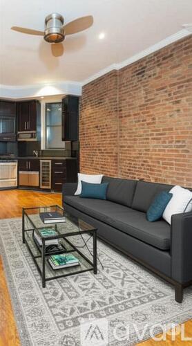 A living room with a grey couch and a brick wall.