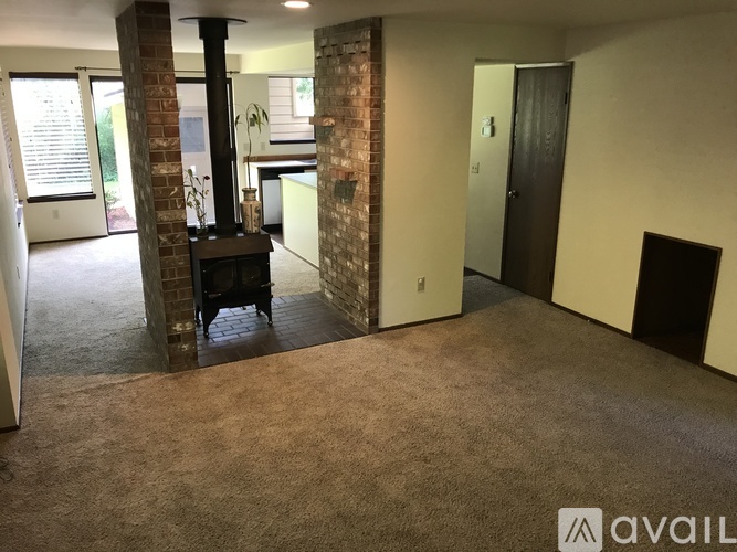 A living room with a fireplace and a brown carpet.