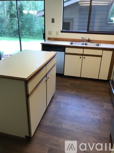 A kitchen with a white counter top and wooden floors.