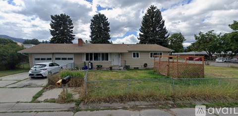 A house with a car parked in front and a fence surrounding the property.