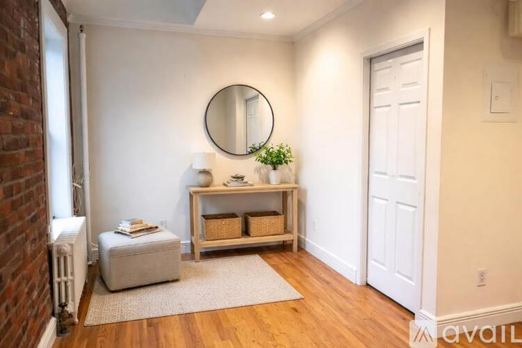 A room with a round mirror on the wall and a wooden bench with baskets on it.