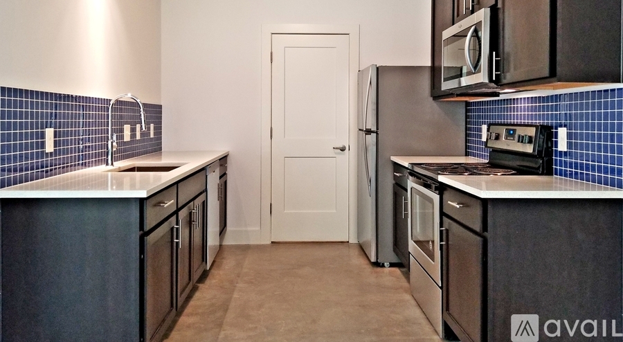 A kitchen with black cabinets and a white door.
