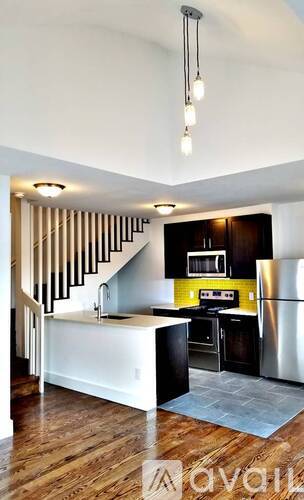 A kitchen with a staircase in the background.