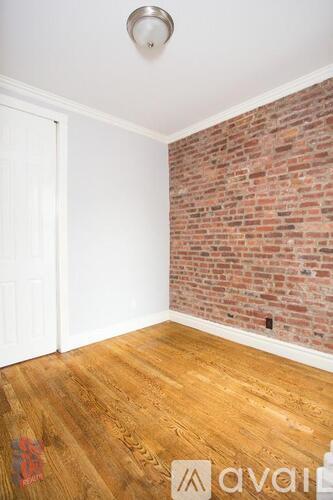 A room with a wooden floor and a brick wall.