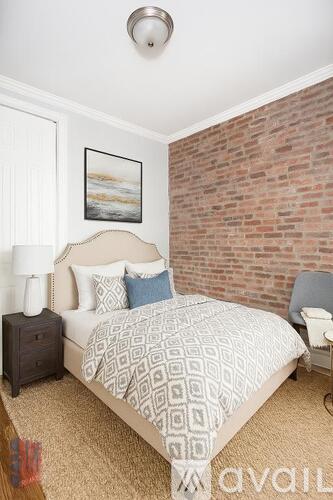 A bedroom with a brick wall and a bed with a white comforter.