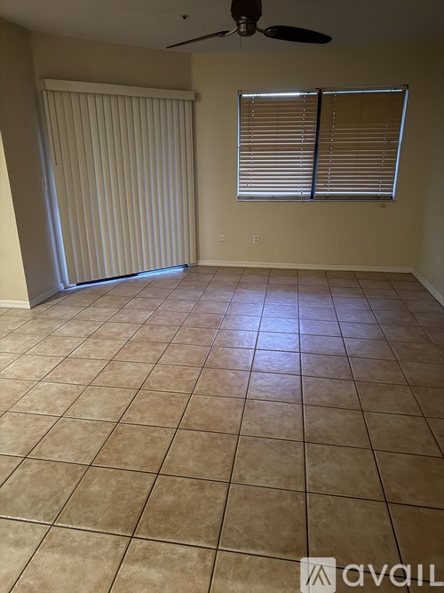A room with tiled flooring and a window with blinds.
