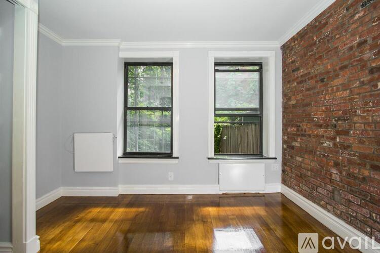 A room with a brick wall and two windows.