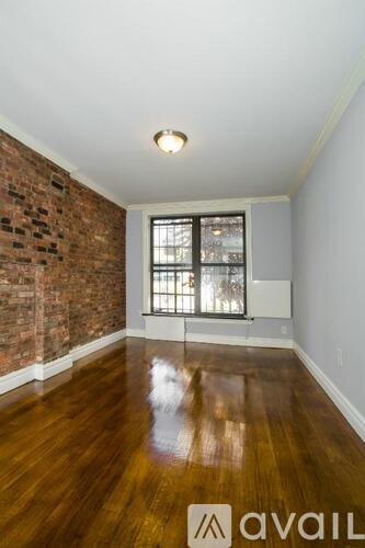 A room with a wooden floor and a brick wall.