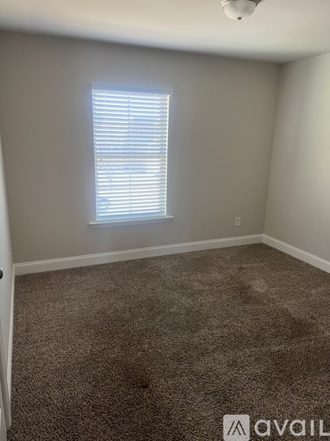 A room with a carpeted floor and a window with blinds.