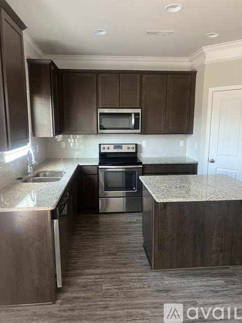 A kitchen with dark brown cabinets and a stainless steel oven.