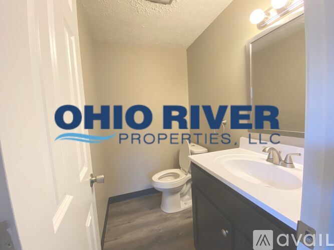 A bathroom with a toilet, sink, and mirror with the words Ohio River Properties LLC on the wall.