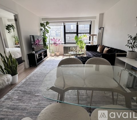 A modern living room with a glass table and grey chairs.