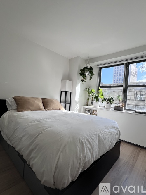 A bedroom with a large bed and a window overlooking a cityscape.