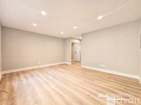 A spacious room with wooden flooring and a door in the background.