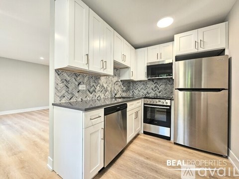 A modern kitchen with white cabinets and stainless steel appliances.