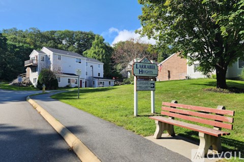 A bench is on the side of a road in front of a sign that says LARRABEE HIGH SCHOOL.