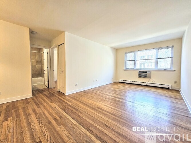 A room with wooden flooring and a window with blinds.