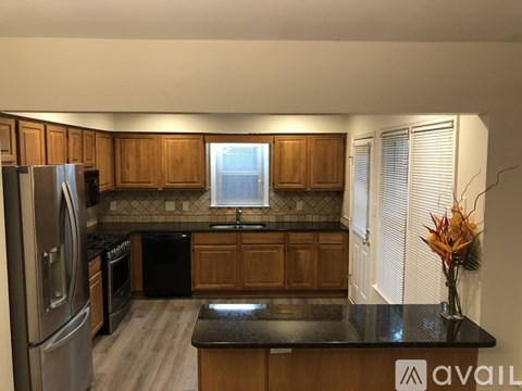 A kitchen with wooden cabinets and a black countertop.