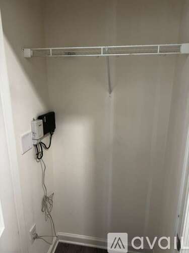 A white wall with a white shelf and a white outlet.