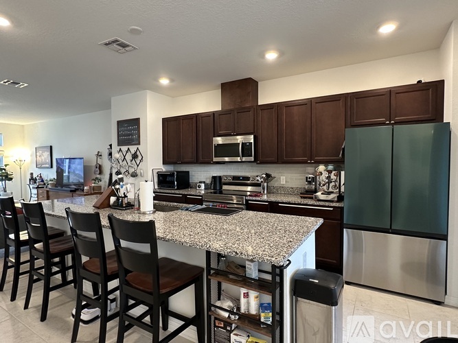 A kitchen with a granite countertop and dark brown cabinets.