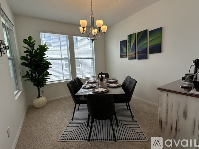 A dining room with a table set for four and a chandelier hanging from the ceiling.