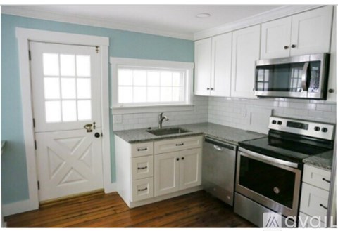 A kitchen with white cabinets and a blue wall.