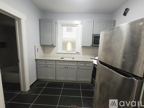 A kitchen with a refrigerator, cabinets, and a window.
