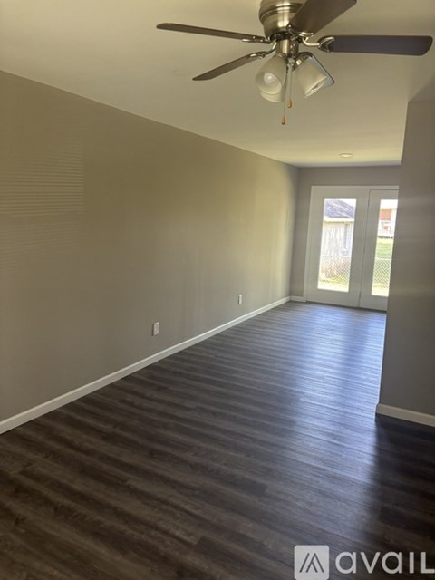 A room with a ceiling fan and wooden flooring.