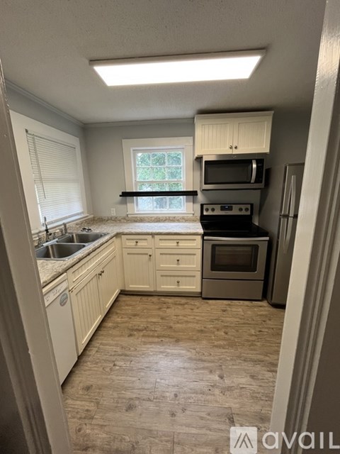 A kitchen with white cabinets and a window.