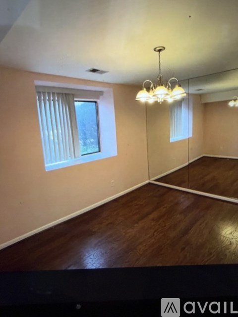 A room with wooden floors and a window with blinds.