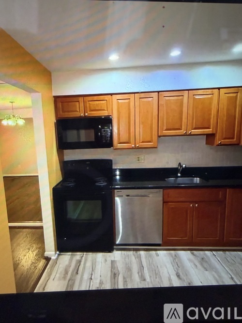 A kitchen with wooden cabinets and a black fridge.