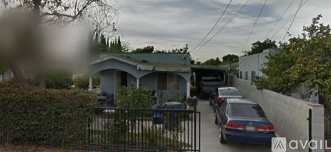 A car is parked in front of a house with a black gate.