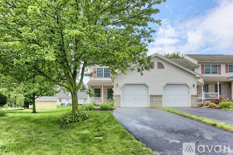 A house with a driveway and a tree in front of it.