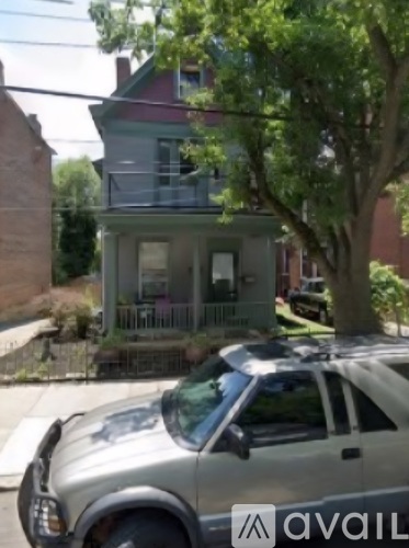 A silver car is parked in front of a house.