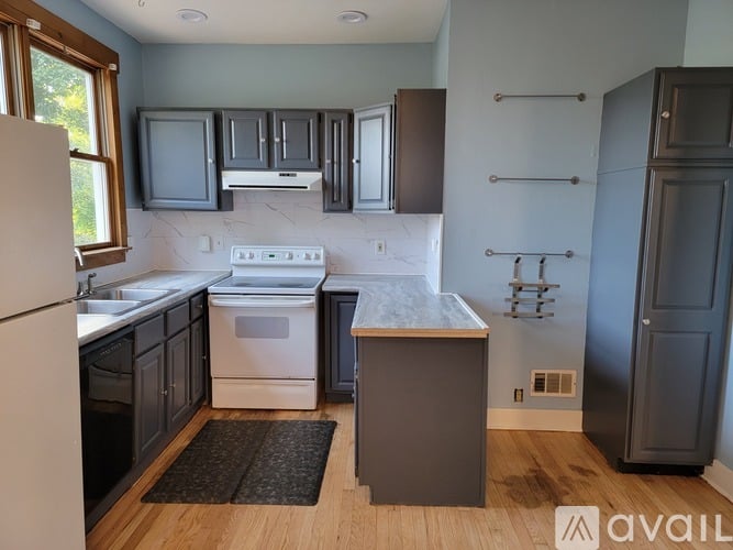 A kitchen with a white stove top oven and a white dishwasher.