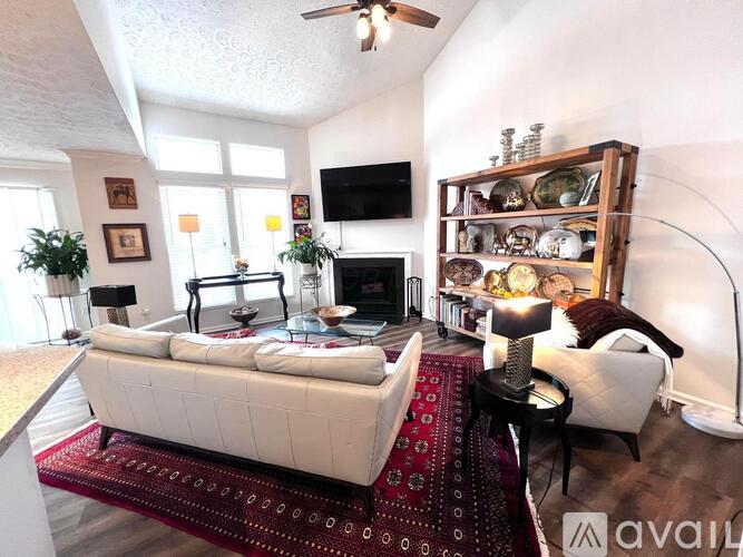 A living room with a white couch and a red rug.