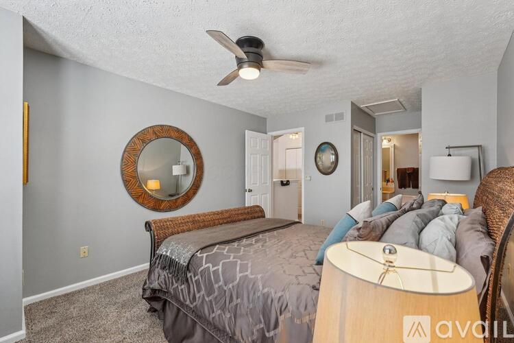 A bedroom with a bed, a ceiling fan, and a mirror on the wall.