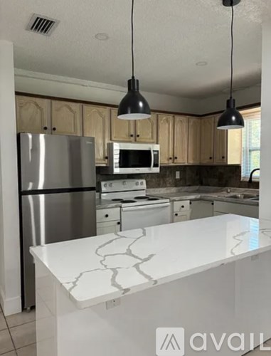 A kitchen with a white island and stainless steel appliances.