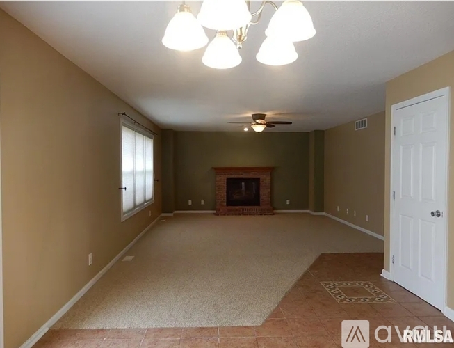 A spacious room with a fireplace and a ceiling fan.