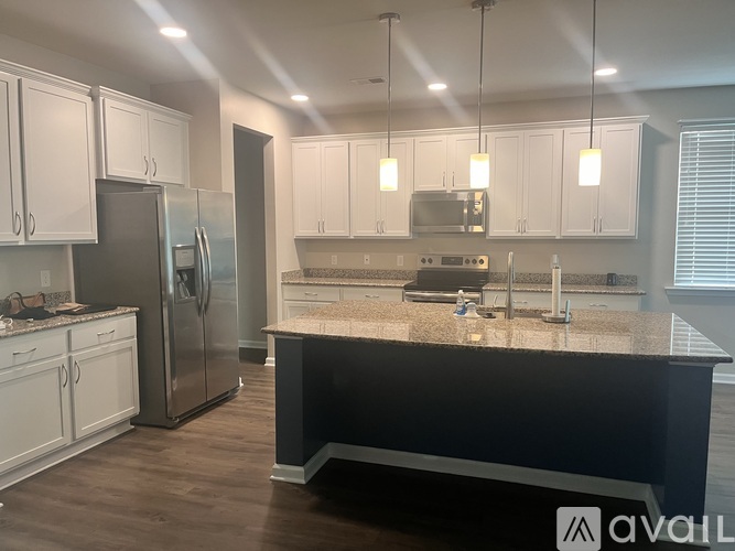 A kitchen with white cabinets and a black island.